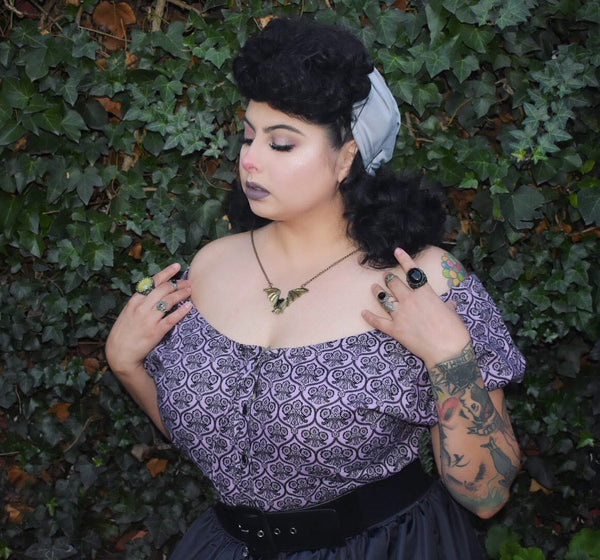 Close-up of a model wearing the Mary Blouse in Lil' Lou Lou's Haunting Wallpaper print featuring an off-the-shoulder neckline and vintage-inspired styling.