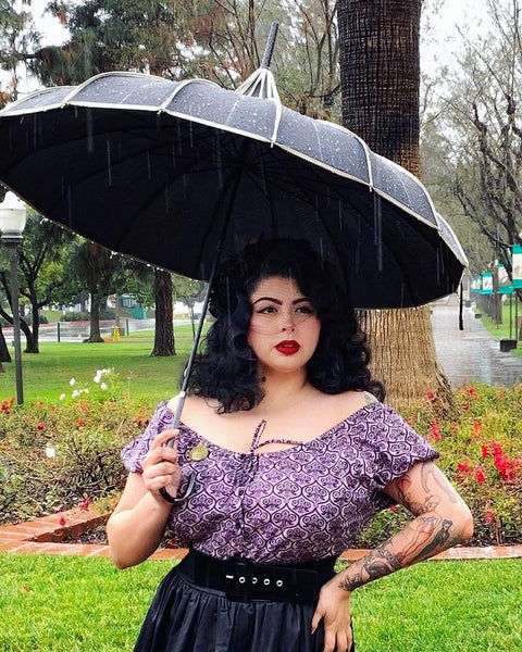 Model wearing Lil' Lou Lou's Mary Blouse in the Haunting Wallpaper print styled off the shoulders with a black skirt and umbrella.
