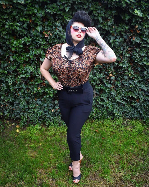 Model wearing the Leopard Mary Blouse by Lil' Lou Lou with high-waisted black pants, showcasing vintage-inspired styling.