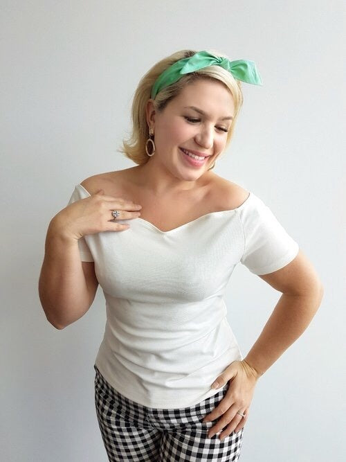Woman wearing Lil' Lou Lou's ivory Rockin' Cori top with off-the-shoulder neckline styled with a mint 4-in-1 headband and gingham capri pants.