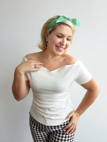 Woman wearing Lil' Lou Lou's ivory Rockin' Cori top with off-the-shoulder neckline styled with a mint 4-in-1 headband and gingham capri pants.