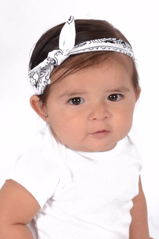 Baby wearing a white rockabilly baby headband with side bow detail