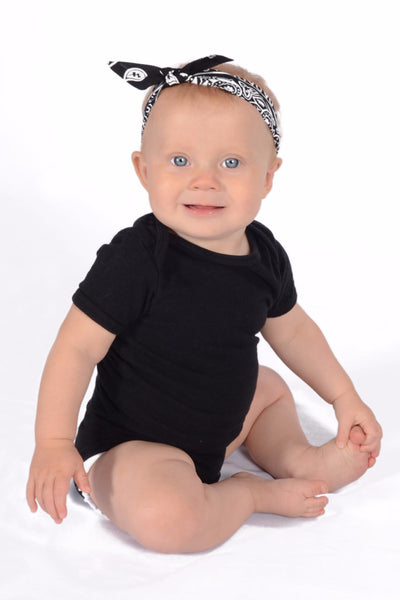 Baby wearing Classic Black 3 in 1 baby headband styled with bow to the side