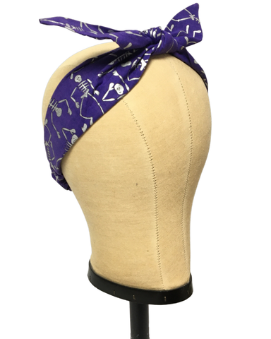 Purple Kids 4-in-1 headband in the Spooky Scary Skeletons skeleton print with removable bow displayed on a mannequin.