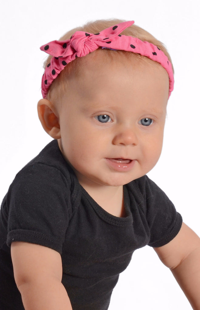 Baby wearing Lil' Lou Lou pink and black polka dot Mommy & Me Headband with a knotted bow detail.