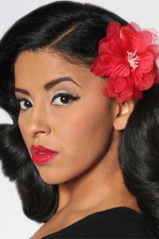 Model wearing a red camellia hair flower styled with a vintage inspired pin up hairstyle.