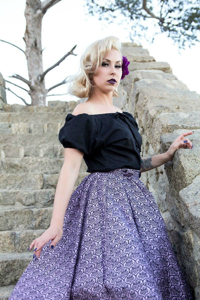 Model wearing the Haunting Wallpaper Jivin' Skirt and black Mary Blouse by Lil' Lou Lou, standing on stone steps and showcasing the vintage-inspired gothic print and full gathered silhouette.
