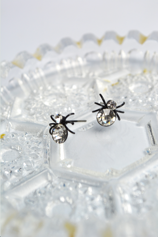 White House Spider stud earrings with crystal accents displayed on a vintage crystal dish. Gothic spider earrings inspired by Lil' Lou Lou's Morticia's Garden collection.