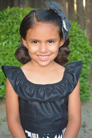 Girl wearing Lil' Lou Lou Cha Cha black ruffle crop top styled with a high waisted skirt, inspired by 1950s children's separates.