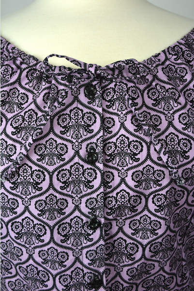 Close-up of the Mary Blouse in the Haunting Wallpaper print showing the elasticized neckline, drawstring ties, and button-front detail.