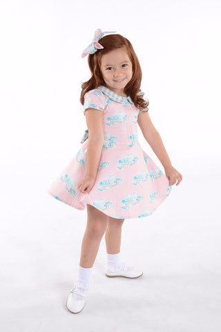 Little girl wearing Lil' Lou Lou Melly Dress in pink Classic Truck print with Peter Pan collar and vintage-inspired twirl skirt