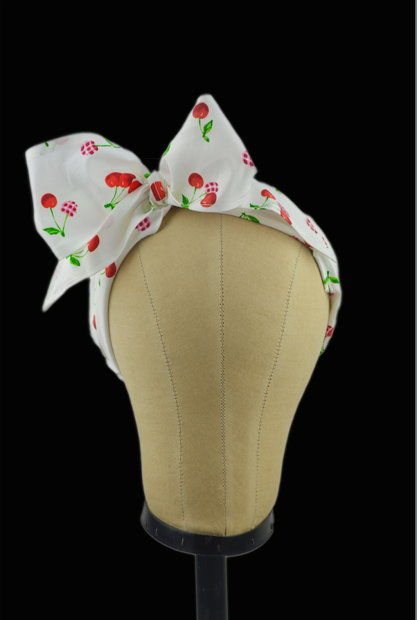 Cherry Delight Minnie Headband featuring a vintage-inspired cherry print, oversized side bow, and retro scarf styling displayed on a mannequin head.