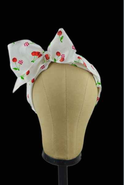 Cherry Delight Minnie Headband featuring a vintage-inspired cherry print, oversized side bow, and retro scarf styling displayed on a mannequin head.