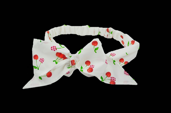 Cherry Delight Minnie Headband with cherry print fabric, oversized bow, wide scarf-inspired band, and elasticized back by Lil' Lou Lou.