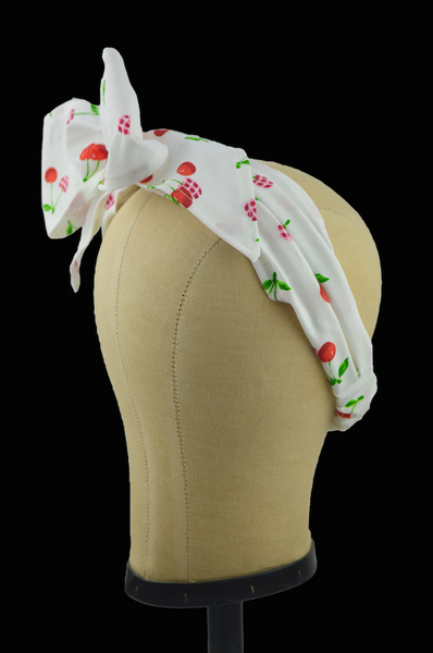 Cherry Delight Minnie Headband side profile showing the vintage scarf-inspired band, oversized bow, and cherry print fabric on a mannequin head.