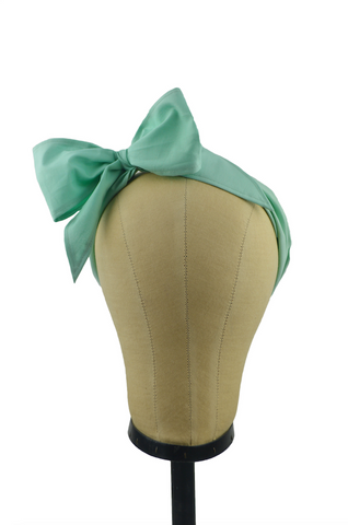 Front view of a seafoam green Minnie Headband with oversized bow displayed on a mannequin head, vintage-inspired cotton hair scarf headband by Lil' Lou Lou.