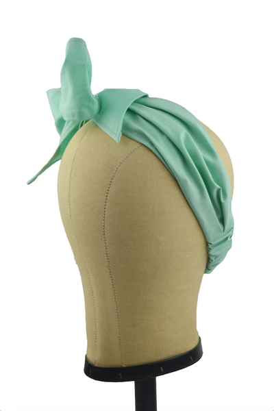 Side view of a seafoam green Minnie Headband with oversized bow displayed on a mannequin head, vintage-inspired cotton hair scarf headband by Lil' Lou Lou.