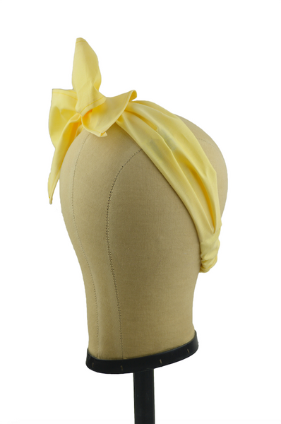 Side view of a yellow Minnie Headband with oversized bow displayed on a mannequin head, vintage-inspired cotton hair scarf headband by Lil' Lou Lou.