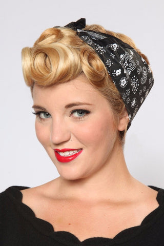 Model wearing the Black Paisley Rosie Bandana featuring black bandana print and signature trim styled with vintage pin curls.