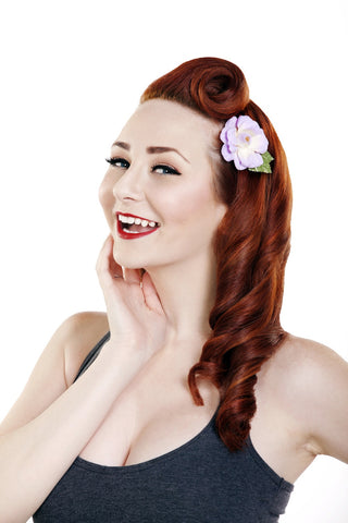 Woman wearing a lilac Rosita hair flower clipped into a retro hairstyle.
